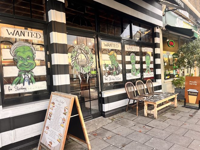The striped frontage with green cartoon villain window decals and an A-board on the pavement
