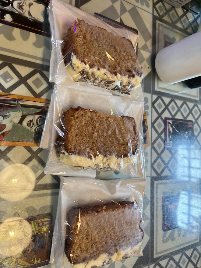 Loaf cake slices stacked in the display case against a geometric tiled wall