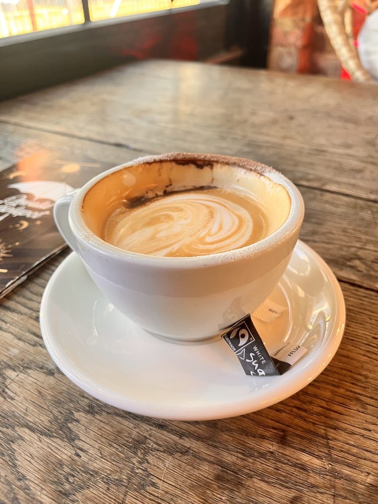 A flat white with latte art in a white cup and saucer